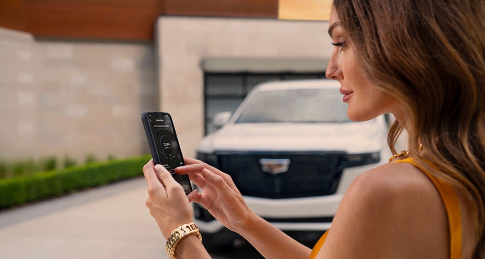 lady checking her mobile with a Cadillac vehicle background | Central Cadillac in Jonesboro AR